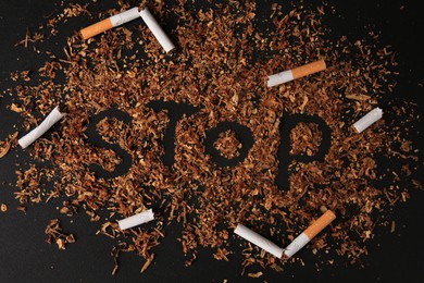 Photo of Word Stop made of dry tobacco and broken cigarettes on dark grey background, flat lay. Quitting smoking concept