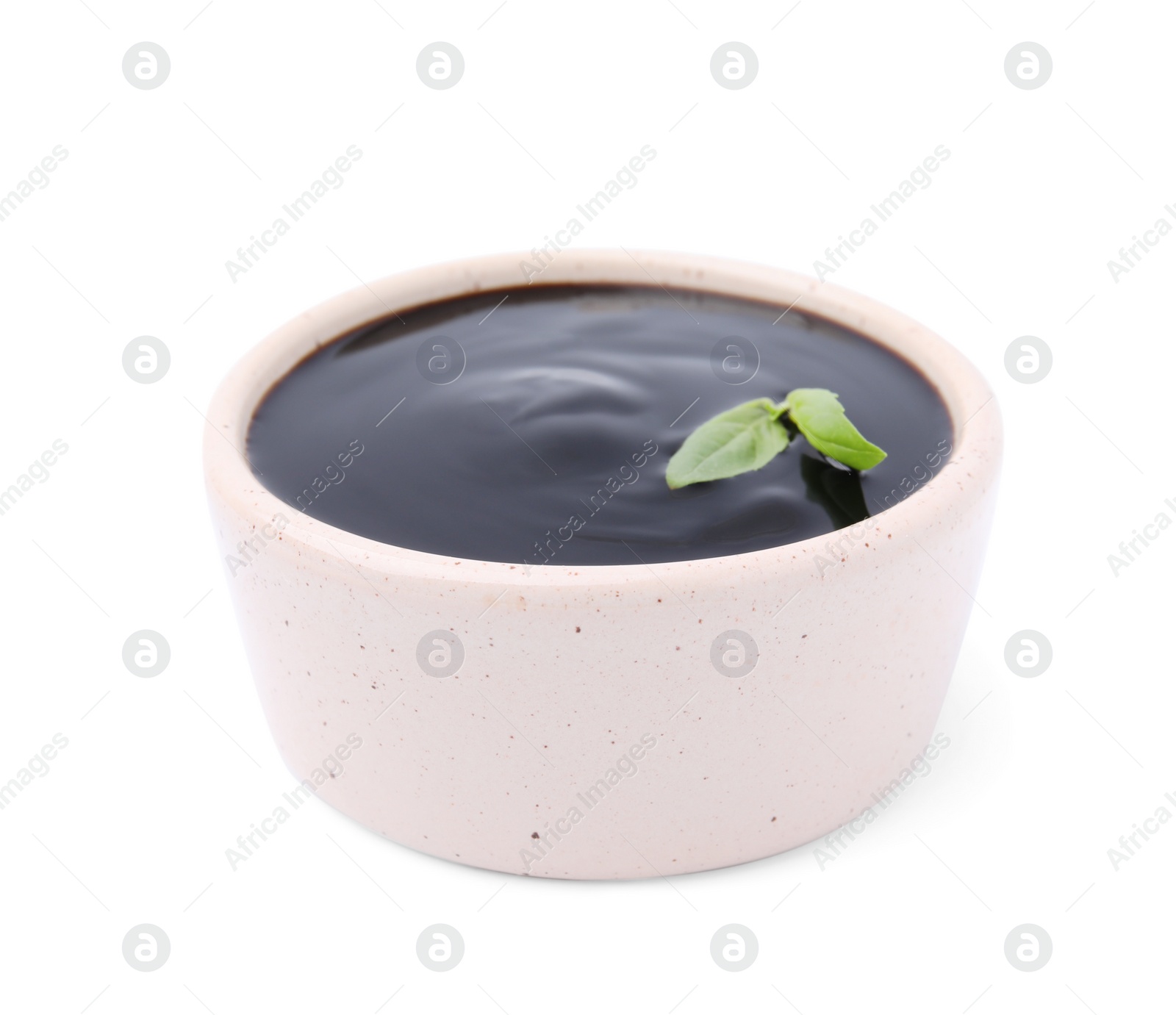 Photo of Balsamic glaze with basil leaves in bowl isolated on white