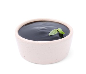 Photo of Balsamic glaze with basil leaves in bowl isolated on white