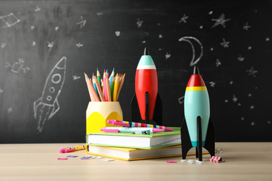 Bright toy rockets and school supplies on wooden table