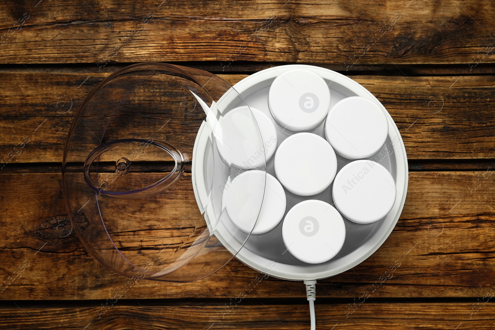 Photo of Modern yogurt maker with jars on wooden table