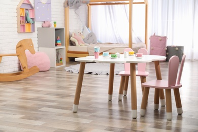 Photo of Toy dishware on small table in playroom. Interior design