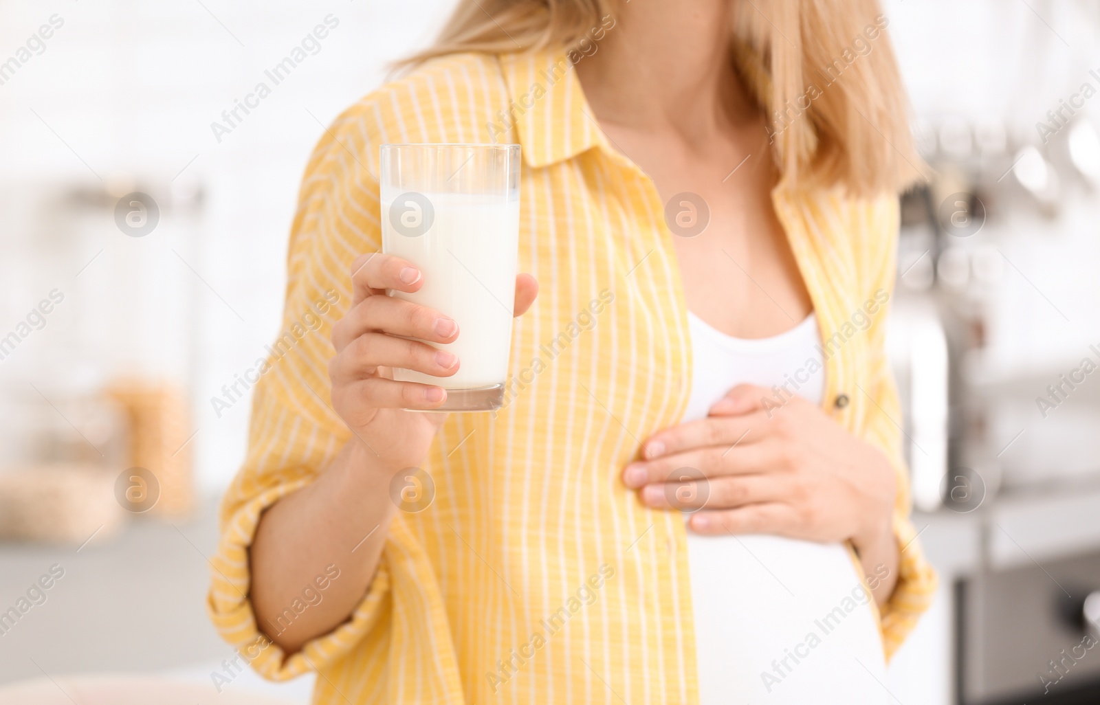 Photo of Beautiful pregnant woman drinking milk in kitchen