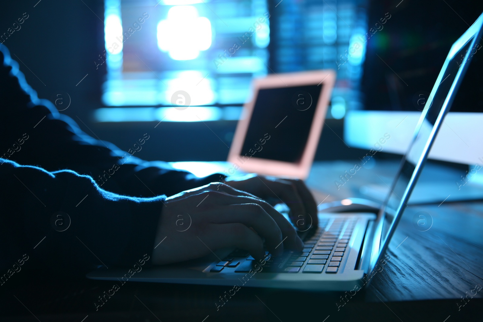 Photo of Hacker with laptop in dark room, closeup. Cyber crime