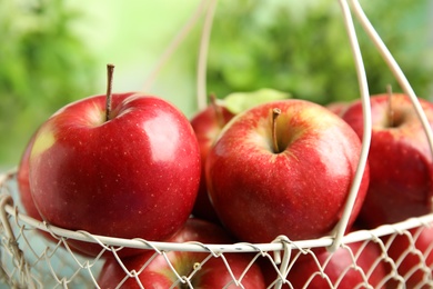 Photo of Metal basket with ripe juicy red apples against blurred background, closeup