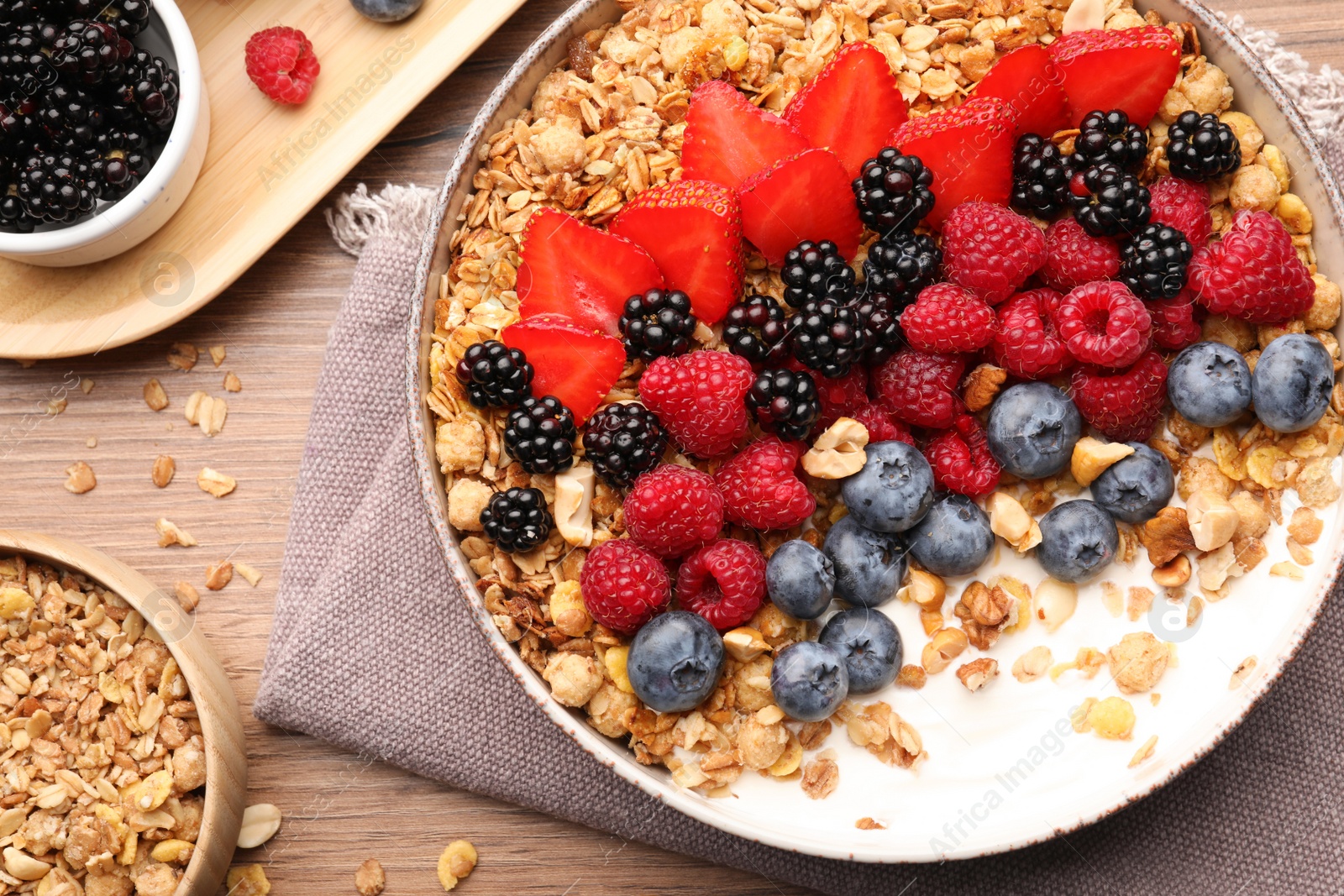 Photo of Healthy muesli served with berries on wooden table, flat lay