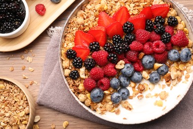 Healthy muesli served with berries on wooden table, flat lay