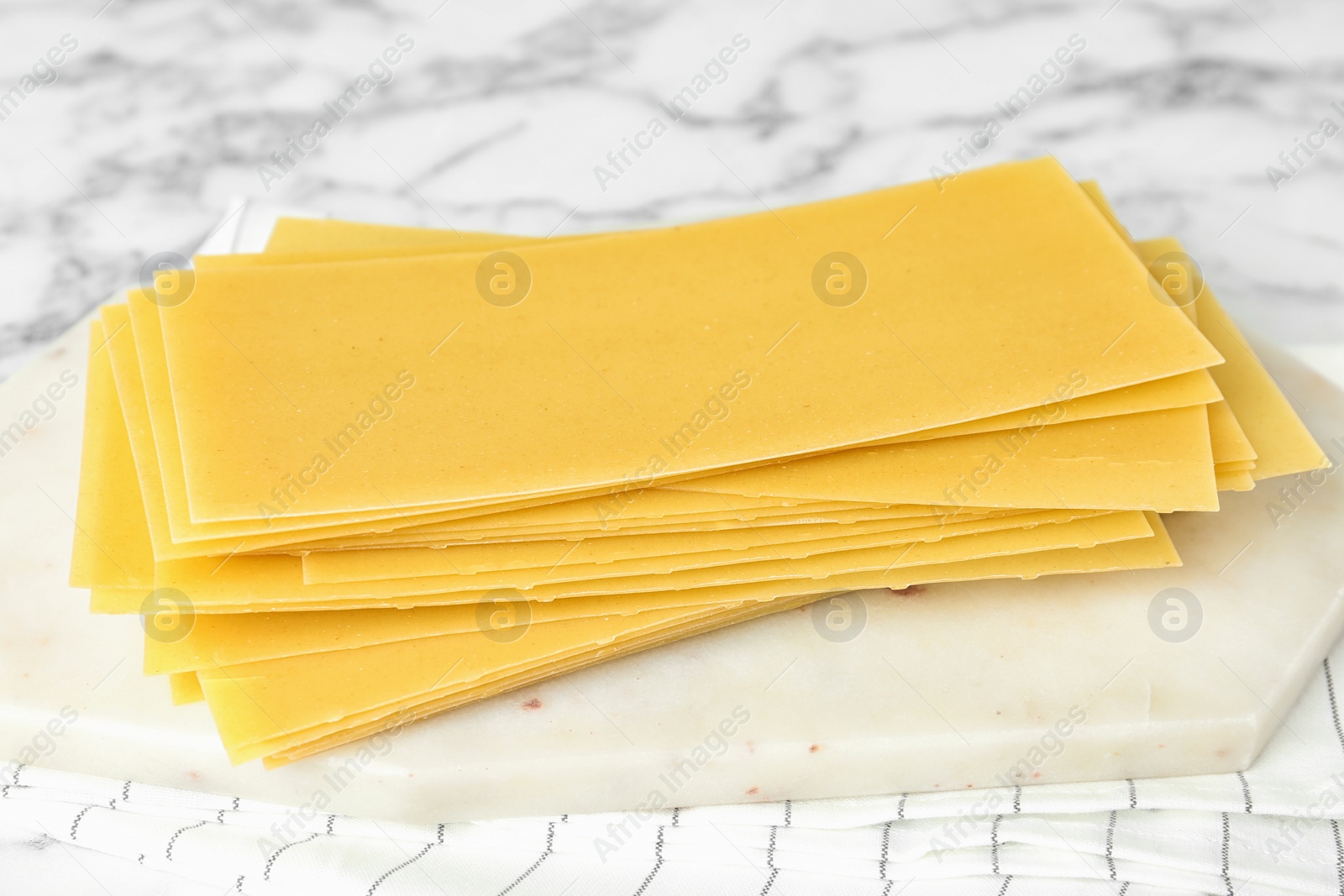 Photo of Uncooked lasagna sheets on white marble table, closeup