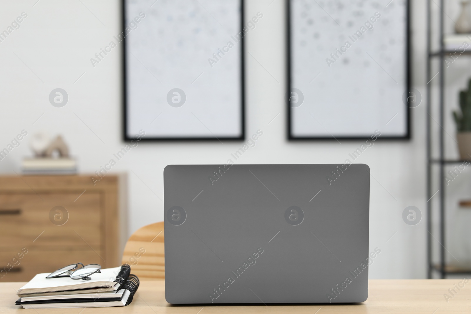 Photo of Home workspace. Laptop, glasses and stationery on wooden desk in room