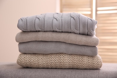 Photo of Stack of folded warm sweaters against blurred background