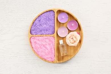 Photo of Compartment plate with aromatic sea salt and different spa products on white wooden table, top view