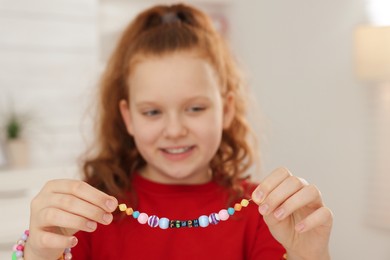 Photo of Girl with bright handmade beaded jewelry in room, focus on hands