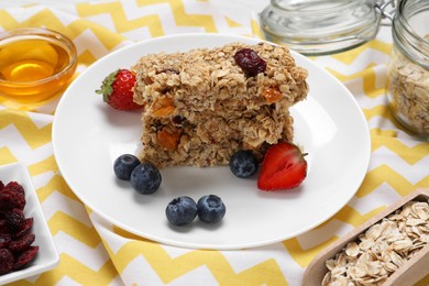 Tasty granola bars with berries and honey on table