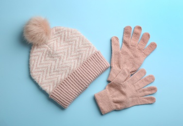Woolen gloves and hat on light blue background, flat lay
