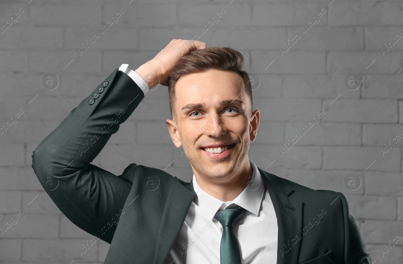 Photo of Portrait of young man with beautiful hair on brick wall background