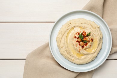 Photo of Tasty hummus with garnish served on white wooden table, top view. Space for text