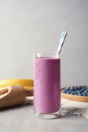 Glass with blueberry smoothie on grey table