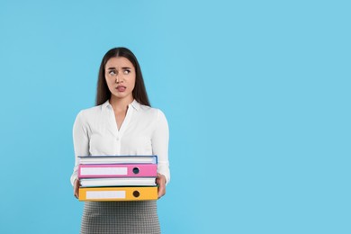 Photo of Disappointed woman with folders on light blue background, space for text