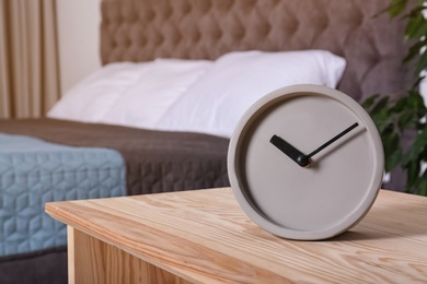 Photo of Stylish alarm clock on nightstand in bedroom. Space for text