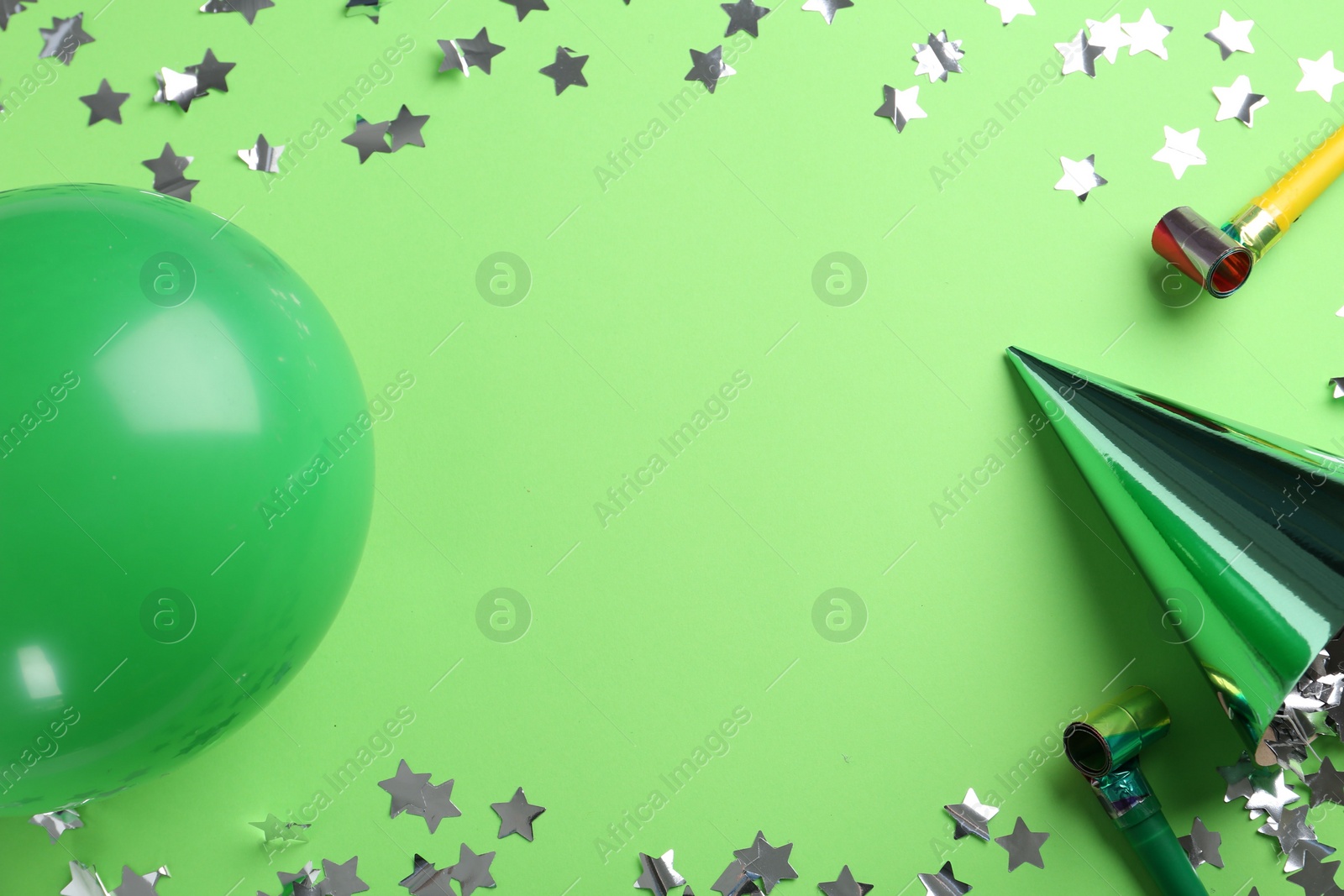 Photo of Frame made of party hat and other bright decor on light green background, flat lay. Space for text
