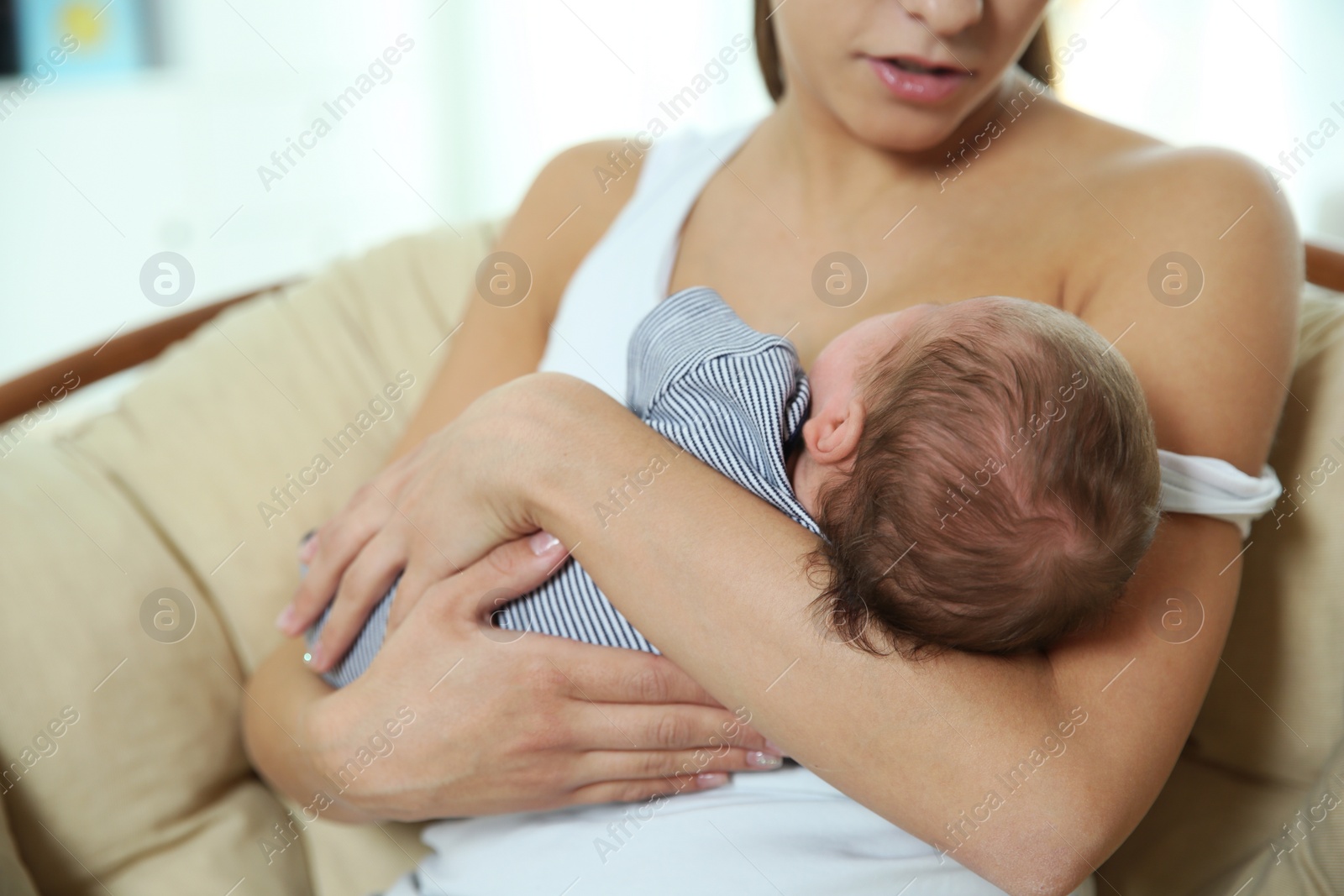 Photo of Young woman breastfeeding her baby at home, closeup