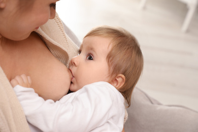 Photo of Woman breastfeeding her little baby at home, closeup