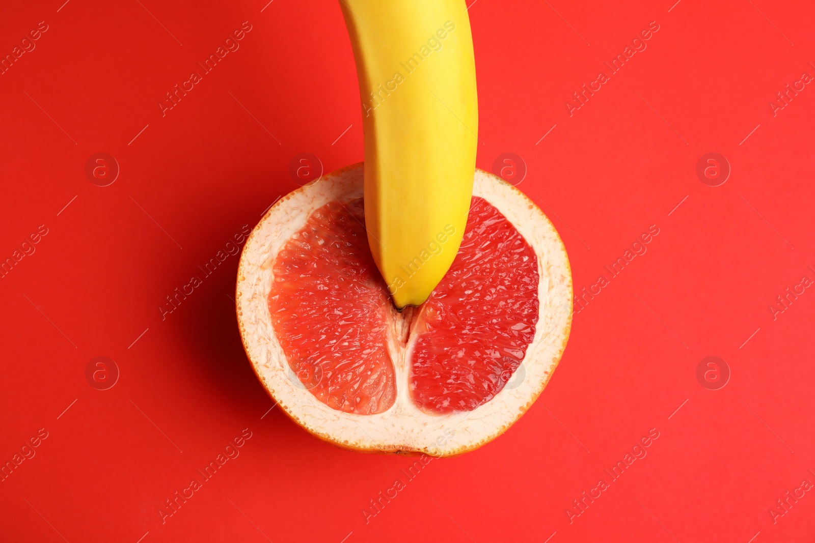 Photo of Fresh grapefruit and banana on red background, top view. Sex concept
