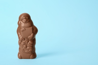 Photo of Unwrapped chocolate Santa Claus on light blue background. Space for text