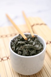 Photo of Chopped nori sheets with chopsticks on white marble table, closeup