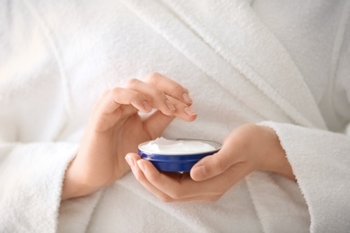Photo of Young woman holding jar with hand cream, closeup