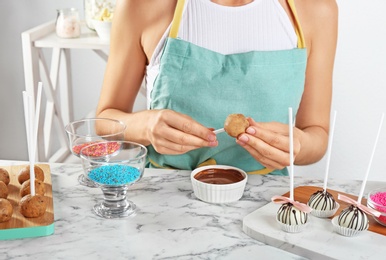 Young woman with cake pop and chocolate frosting at white marble table, closeup