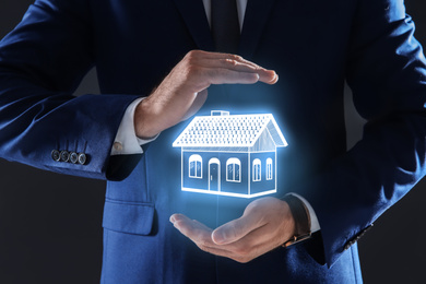 Image of Real estate agent demonstrating house illustration on dark background, closeup