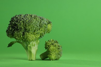 Photo of Fresh raw broccoli on light green background. Space for text