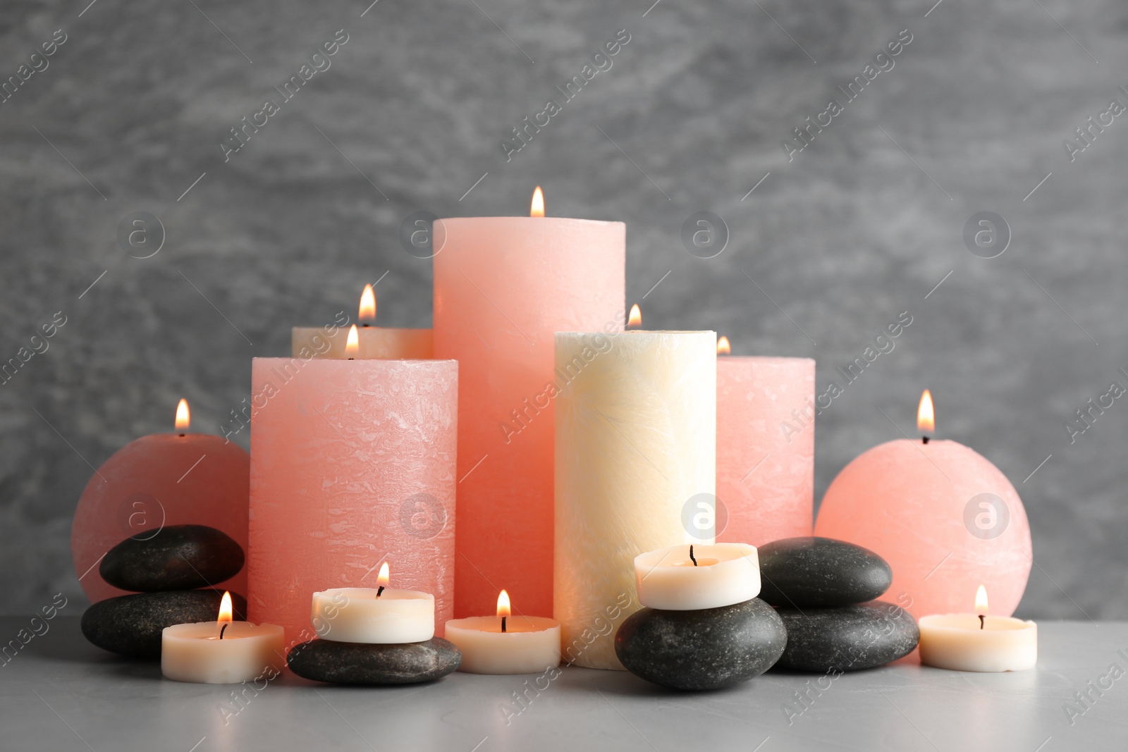 Photo of Beautiful composition with candles and stones on table against grey background