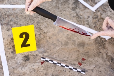 Photo of Detective collecting evidences at crime scene, closeup