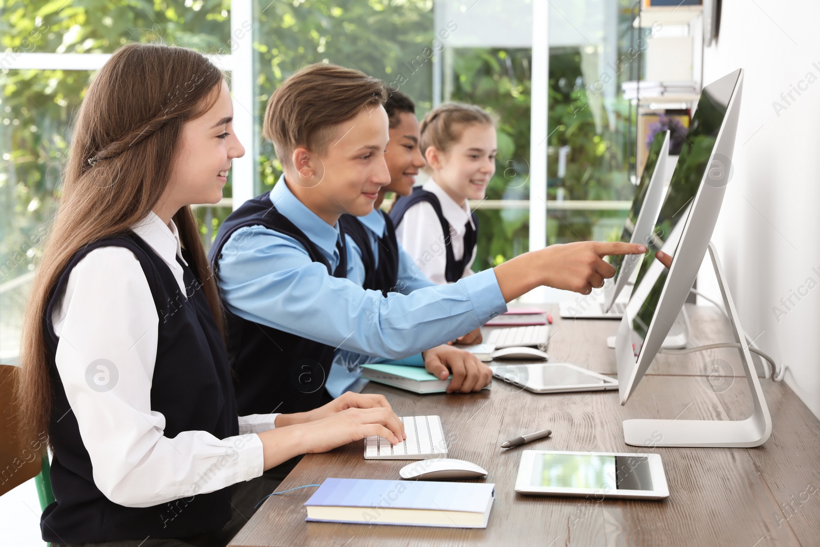 Photo of Teenage students in stylish school uniform at desks with computers