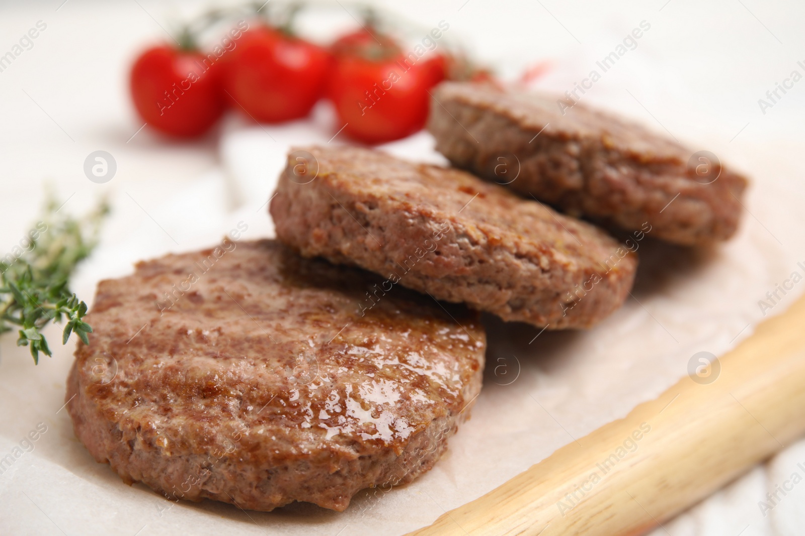 Photo of Wooden board with tasty grilled hamburger patties on table, closeup