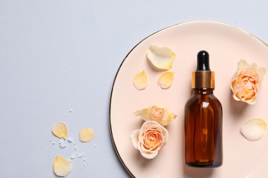 Photo of Bottle of cosmetic serum and beautiful flowers on light grey background, flat lay. Space for text
