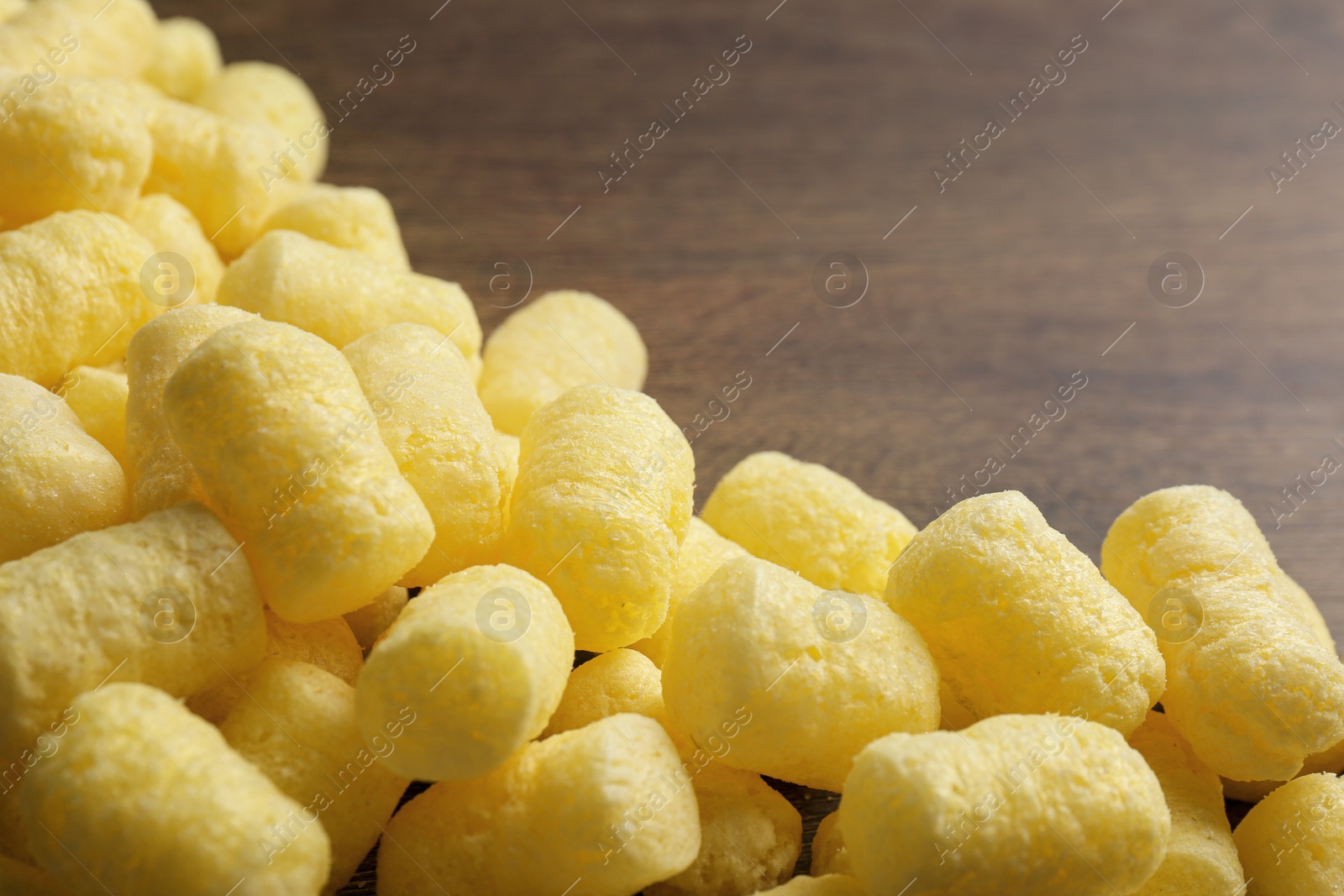 Photo of Pile of delicious crispy corn sticks on wooden table, closeup
