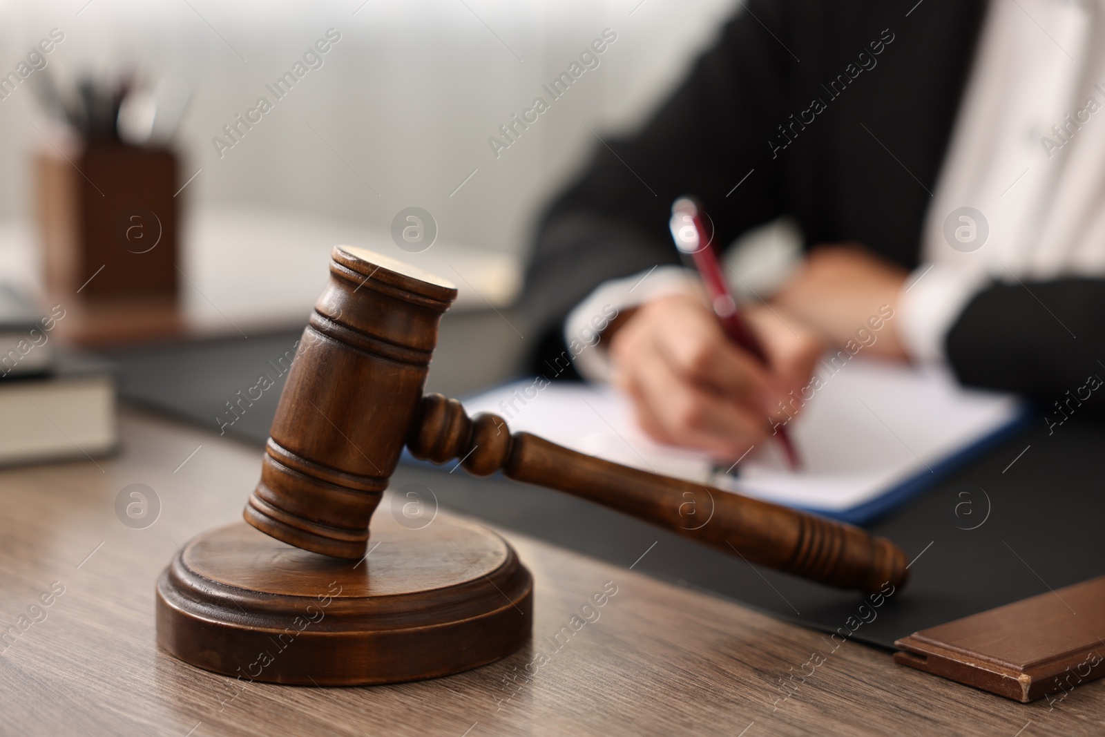 Photo of Notary with clipboard writing notes at workplace in office, focus on mallet