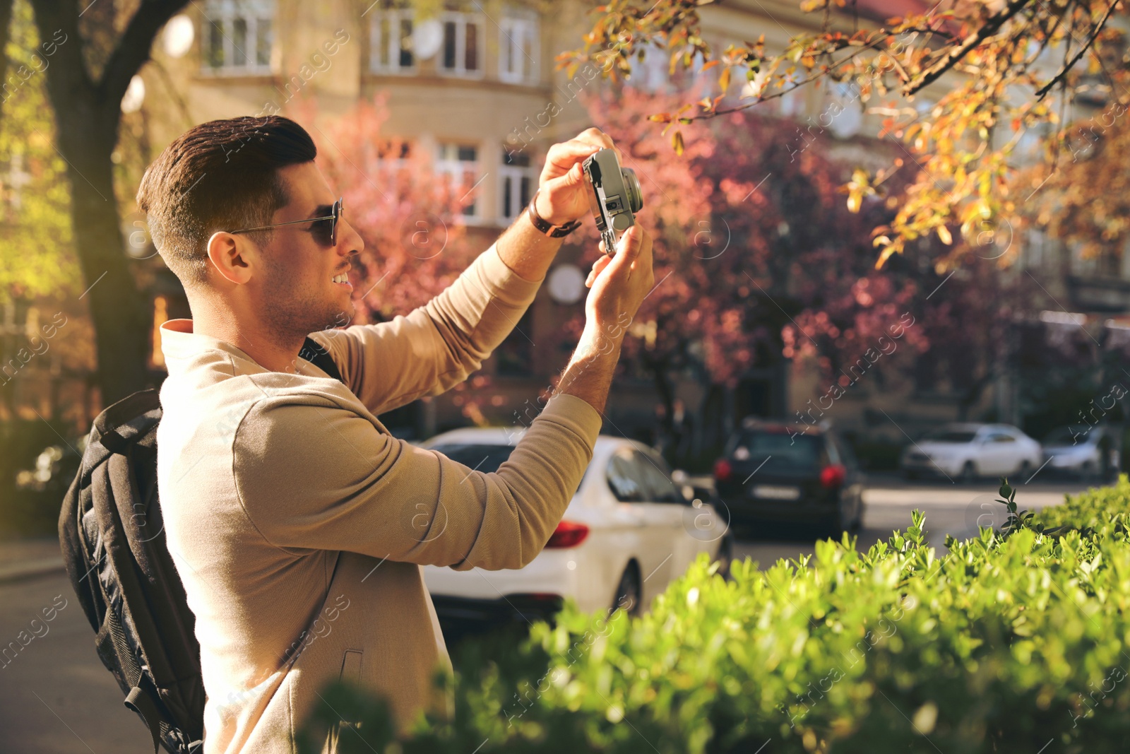 Photo of Happy male tourist with camera on city street