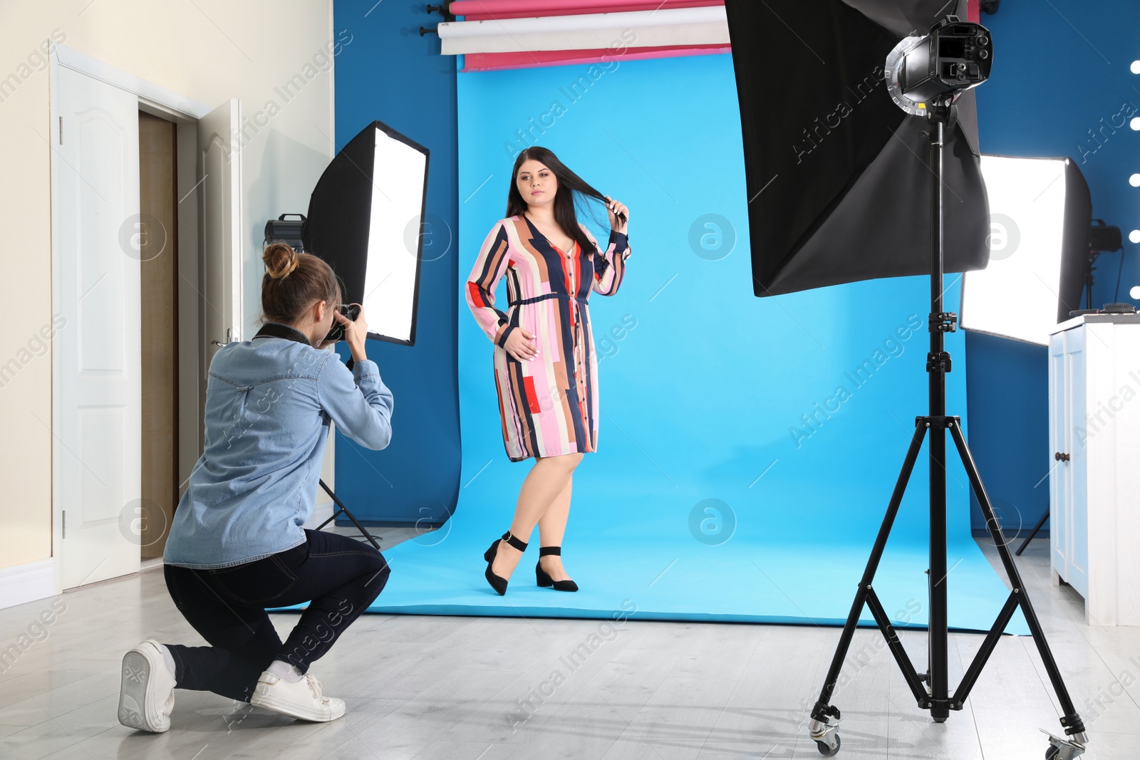 Photo of Photographer taking picture of overweight woman in studio. Plus size model