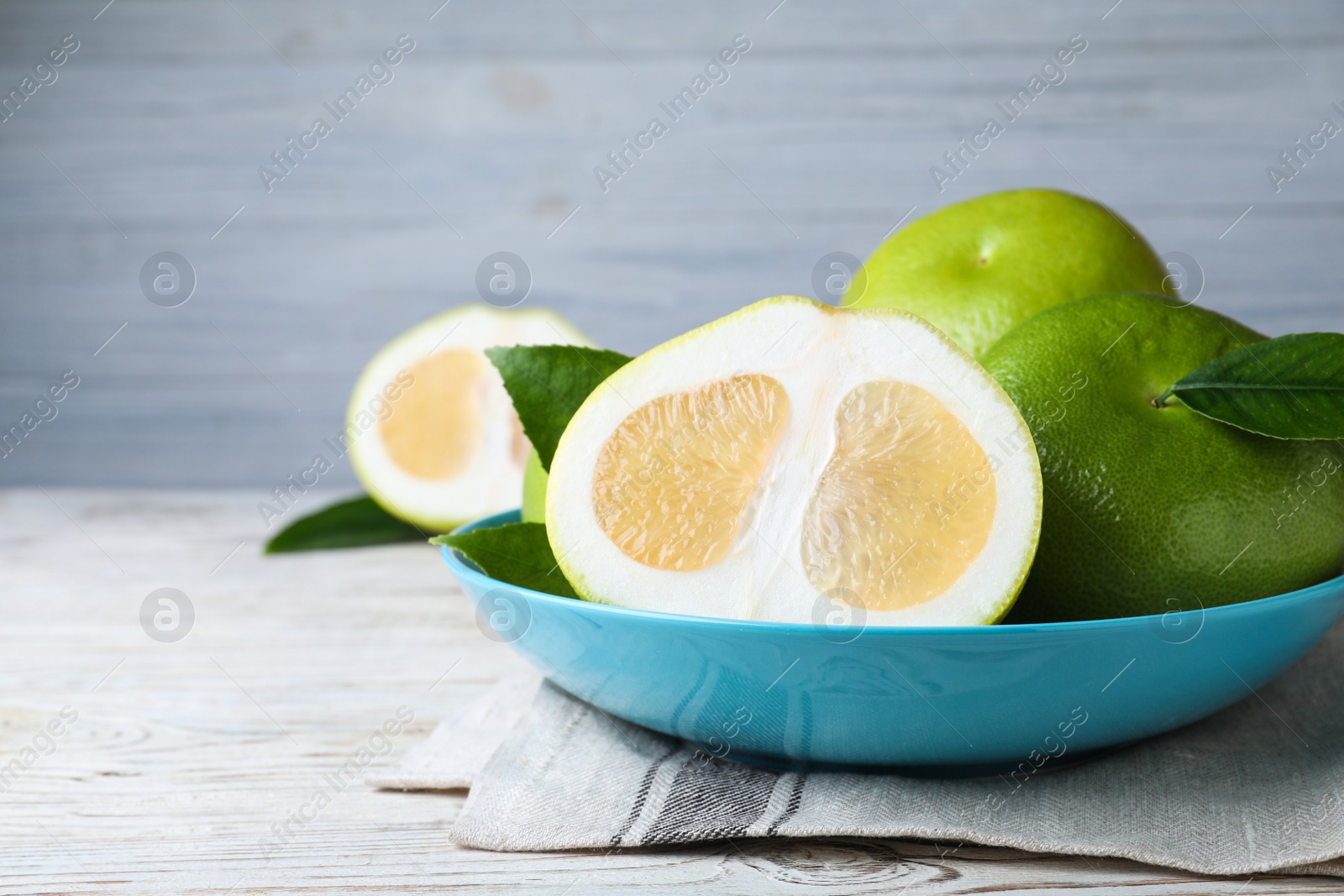 Photo of Whole and cut sweetie fruits on white wooden table