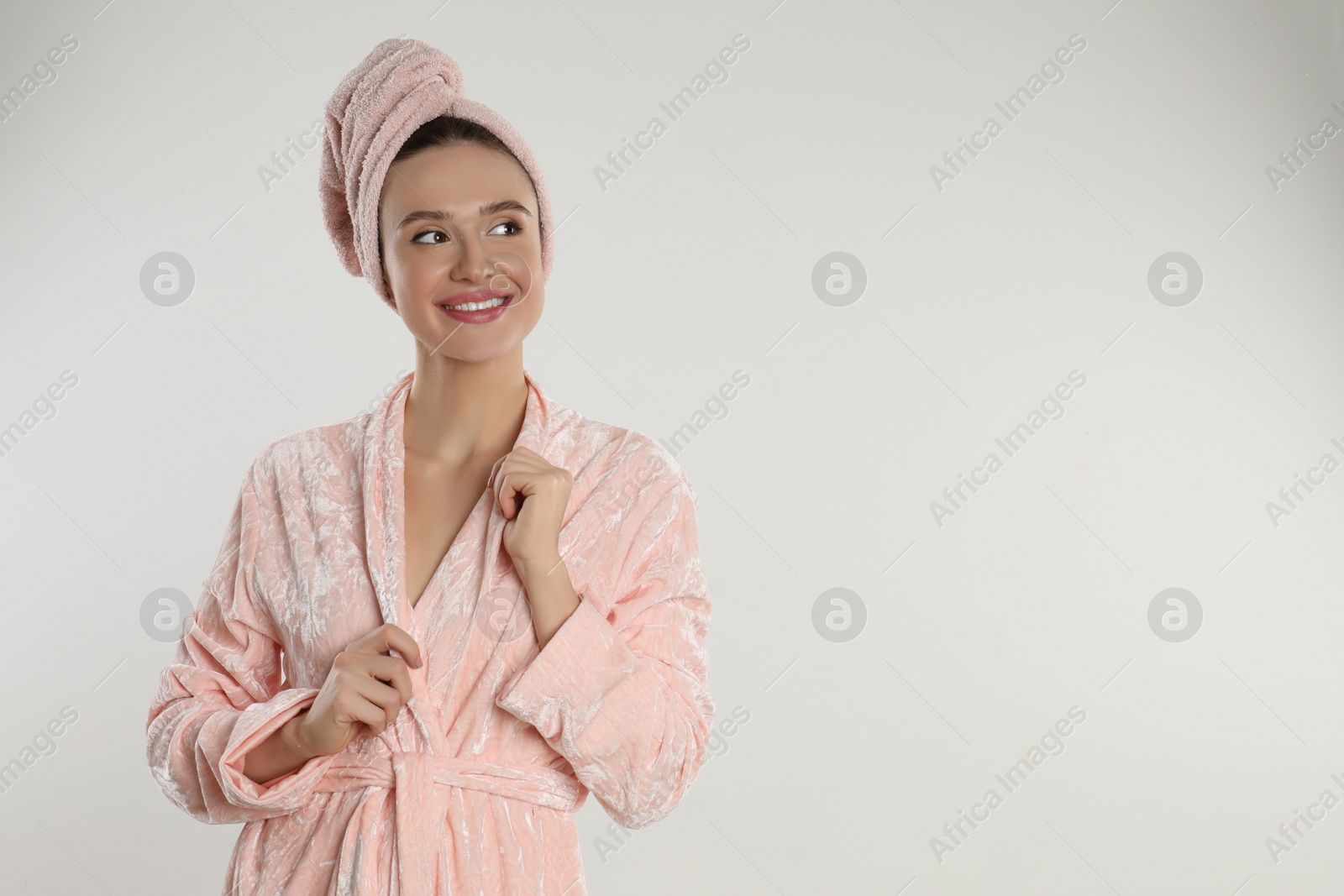 Photo of Beautiful young woman in bathrobe on light background. Space for text