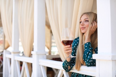 Photo of Beautiful woman with glass of wine on restaurant terrace