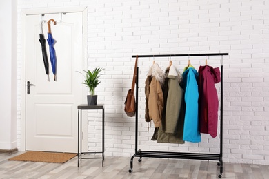 Photo of Stylish hallway interior with clothes on hanger stand