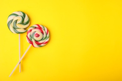 Photo of Colorful lollipops on yellow background, flat lay. Space for text