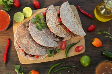 Photo of Delicious tacos with meat and vegetables on wooden table, flat lay