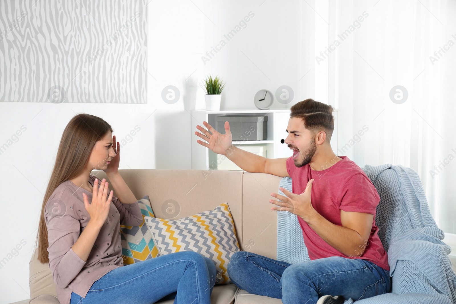 Photo of Young couple arguing in living room. Relationship problems