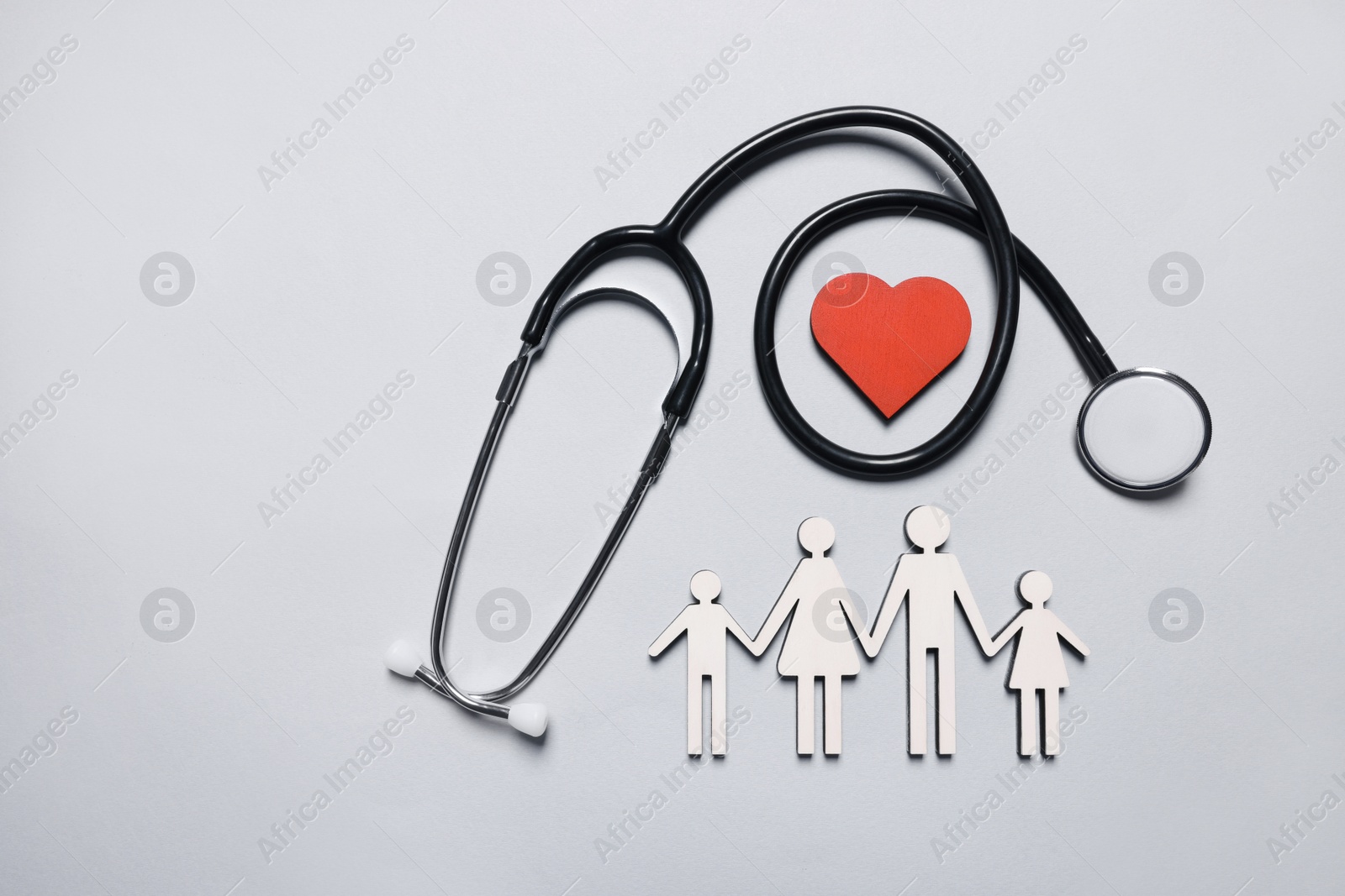 Photo of Figures of family near stethoscope and heart on white background, flat lay. Insurance concept